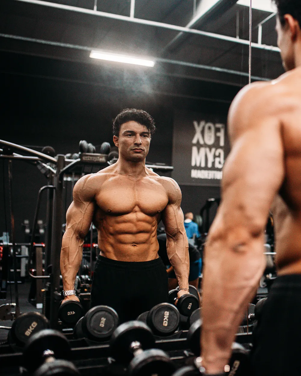 Ugur Cevher bij het dumbbellrek, in de spiegel van de gym